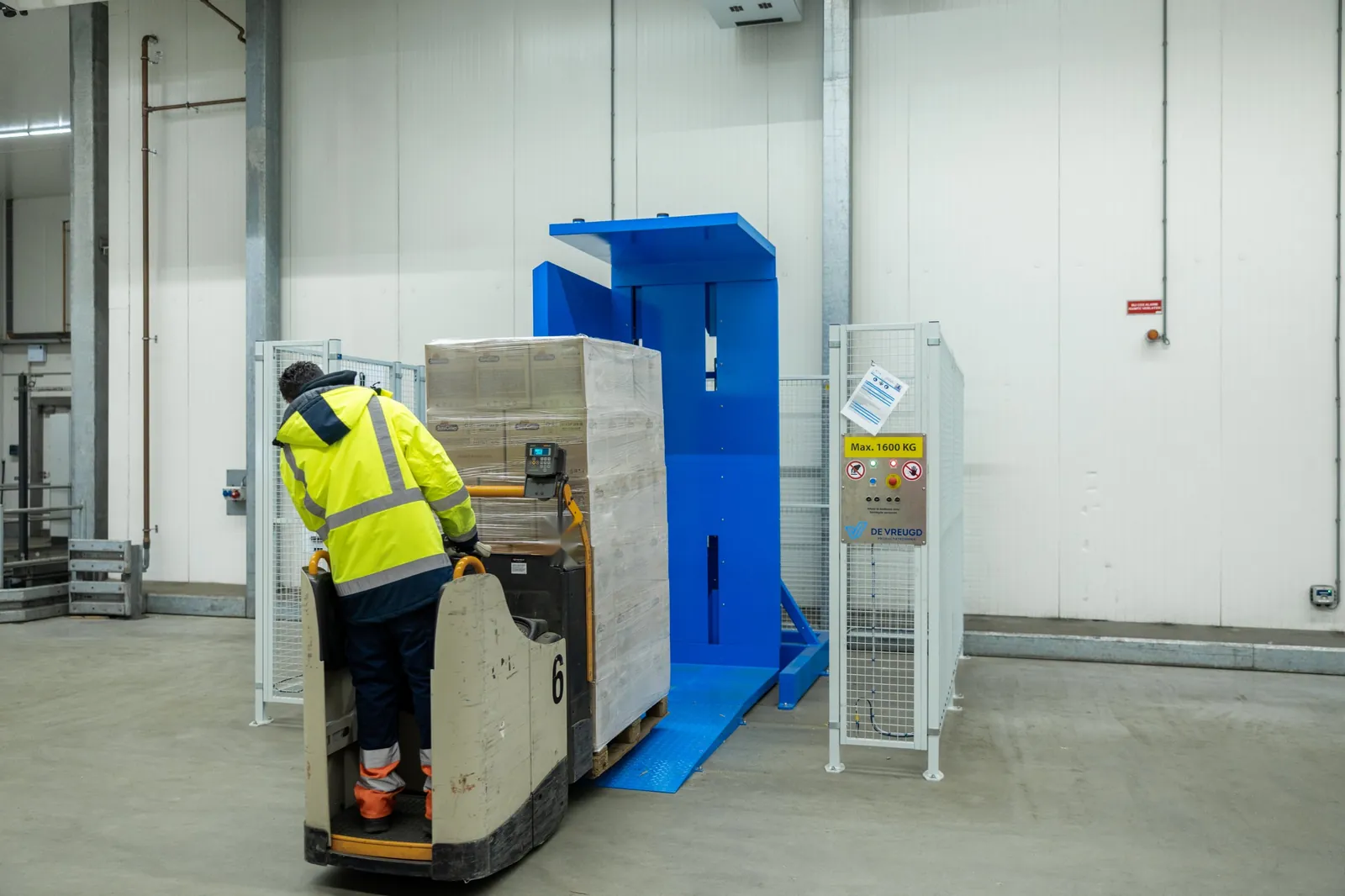 Un employé monte avec un transpalette électrique et une palette sur la rampe du retourneur de palettes PalletRotator EPT
